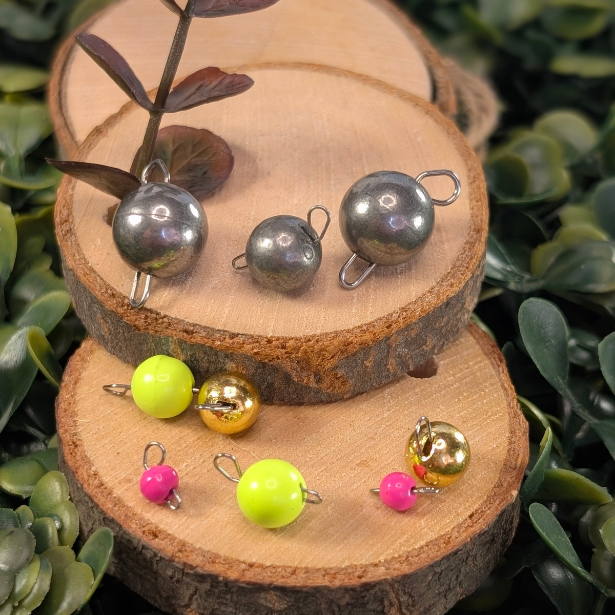 Unpainted, gold, chartreuse, and pink Cheburashka articulated jig weights displayed on stacked wood slices.