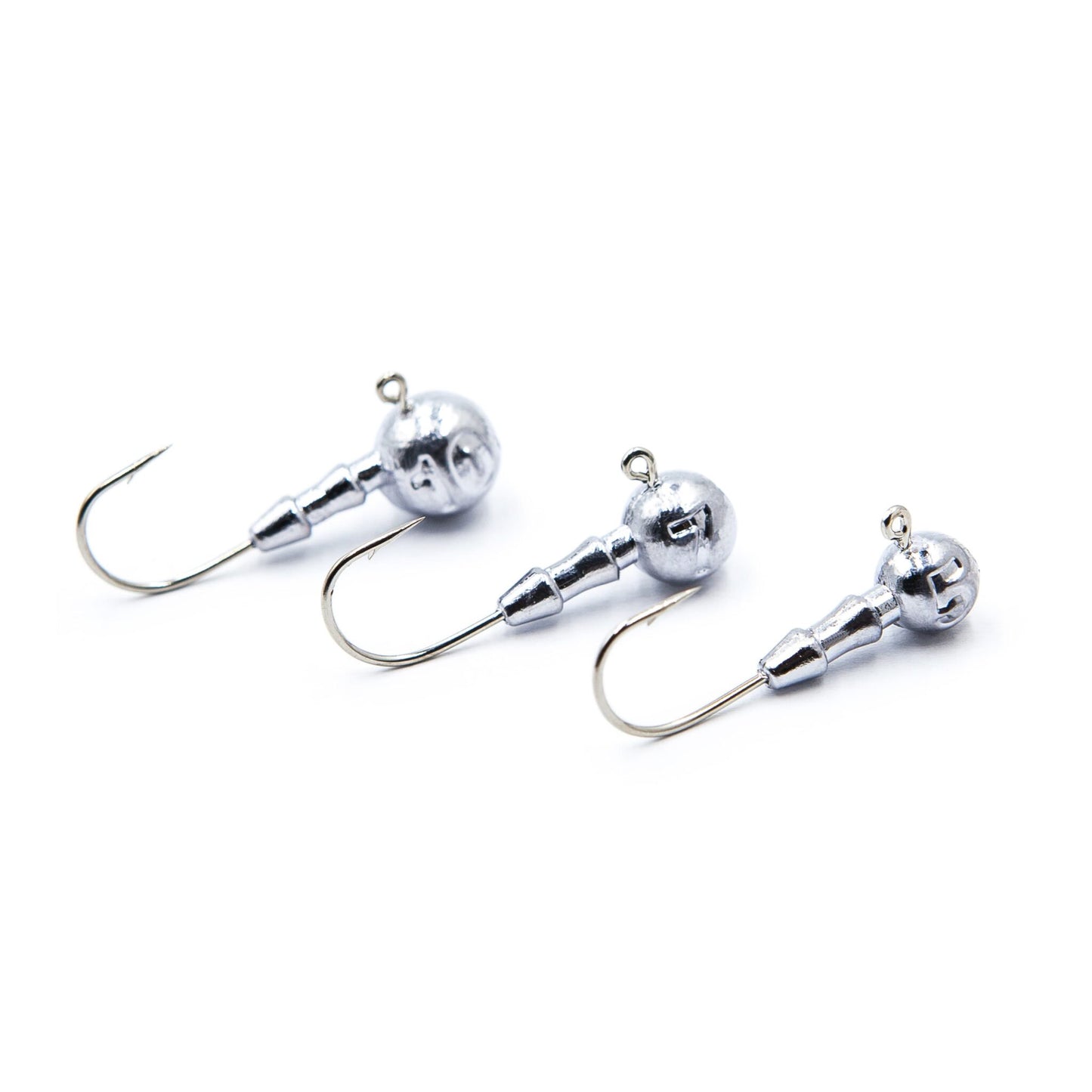 Three silver fishing jigs on a white background