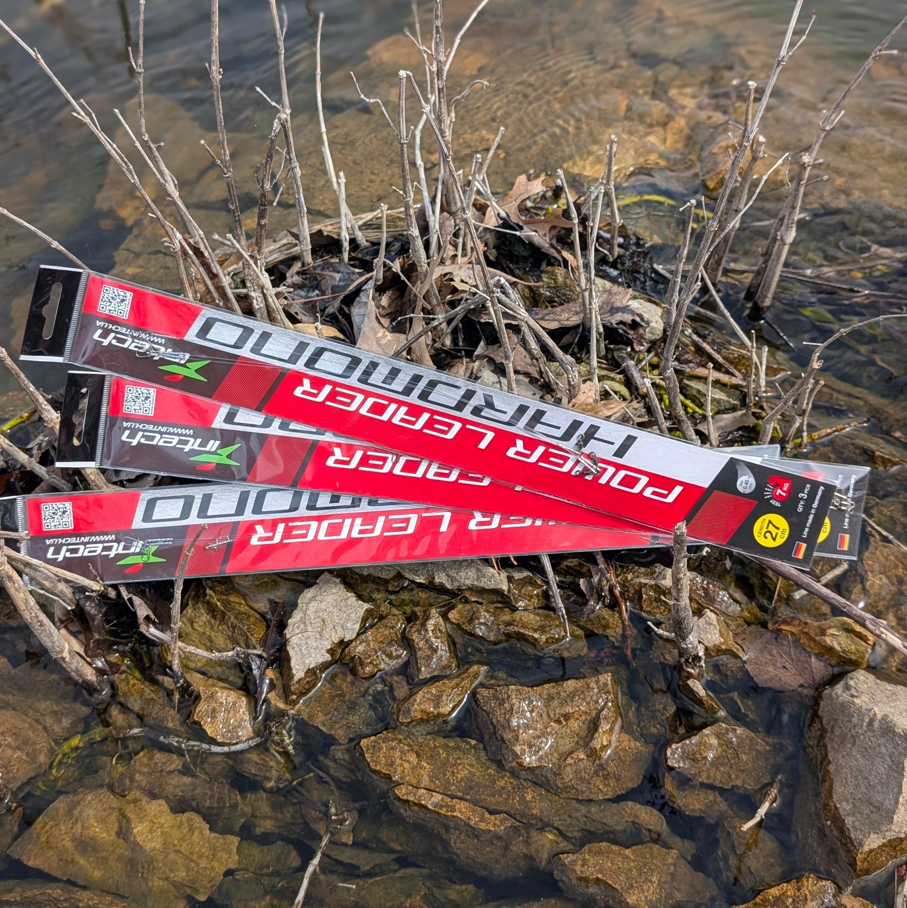 Packaged fishing lures on a rocky shoreline with water in the background