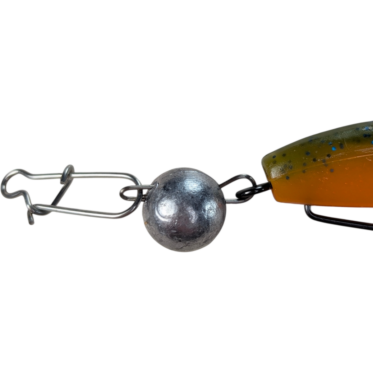Close-up of an unpainted FishTrailCo Fishball articulated jig weight, with a fishing snap attached to one wire loop and a hook rigged with an orange and olive soft plastic bait attached to the other.